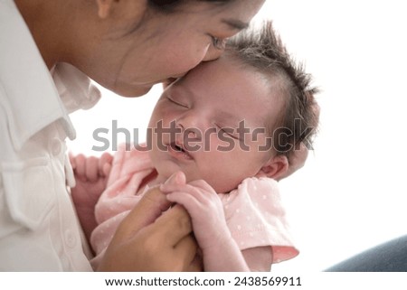 Asian mother teasing with her newborn baby nose to nose while she sleeps, newborn baby less than a month old