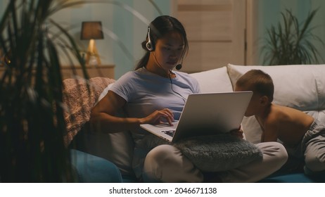 Asian mother using laptop near son - Shutterstock ID 2046671138