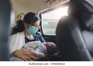 Asian Mother Wearing Protective Face Mask Holding Adorable Newborn Baby Boy While Sitting In The Car. Young Mom Breastfeeding Her Son.