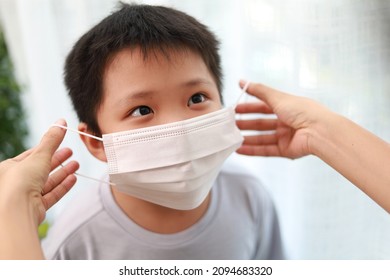 An Asian Mother Wearing A Protective Face Mask For Her Son Before Leaving House To School.