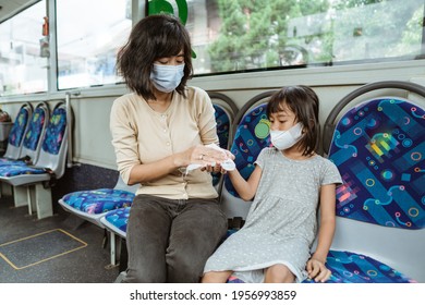 Asian Mother Wears A Mask With Her Daughter While Using A Tissue To Clean Her Hands While Sitting On The Bus