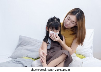 Asian Mother Wiping Her Sick Daughter Nose with Tissue  - Shutterstock ID 2195110035