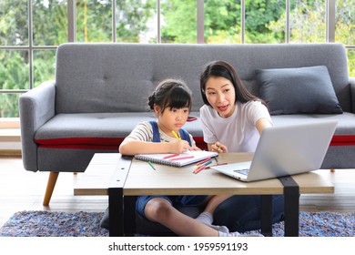 Asian Mother Working Online From Home Using Laptop While Watching Her Daughter Working On Art Class Assignment From School For Homeschooling And Education Concept