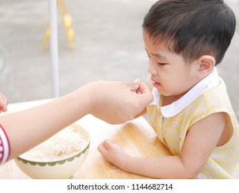 Asian Mother's Hand Introducing A Small Peice Of Crispy Deep-fried Rice Noodle To Her Little Daughter For The First Time - Baby's Development Through Encouraging Them To Try New Foods / Things