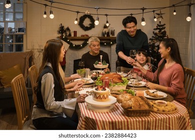 an asian multi-generational family joyfully gathers around a festive dinner table, celebrating christmas or thanksgiving, sharing love and happiness amidst a warm and decorated holiday ambiance - Powered by Shutterstock