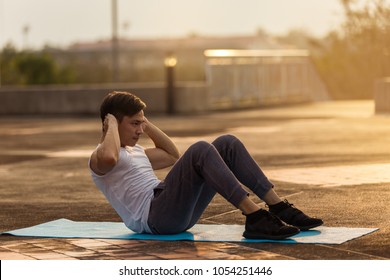 Asian Muscular Man Exercising Doing Sit Up Exercise. Athlete With Six Pack, White Shirt