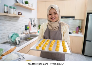 asian muslim beautiful woman with hijab making nastar cake for eid mubarak. tray full of homemade snack