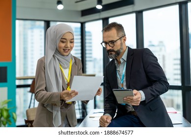 Asian Muslim business woman in hijab headscarf presenting of her work to corporate colleagues in the modern office. diverse corporate colleagues and multicultural - Shutterstock ID 1888674577