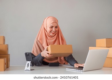 Asian Muslim businesswoman checks stock orders and saves them on her home office laptop. small business owner Shipping in online markets The concept of freedom in life - Powered by Shutterstock