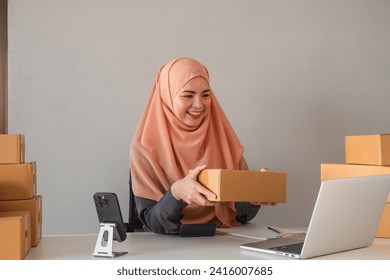 Asian Muslim businesswoman checks stock orders and saves them on her home office laptop. small business owner Shipping in online markets The concept of freedom in life - Powered by Shutterstock