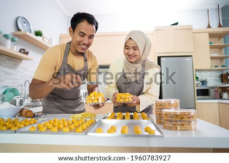 asian muslim couple making nastar snack cake together in the kitchen during ramadan for eid celebration mubarak with family. indonesian food traditonal