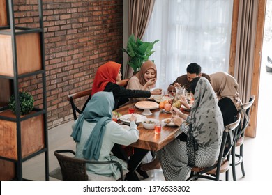 Asian Muslim Family Break Fasting Together In Dining Room