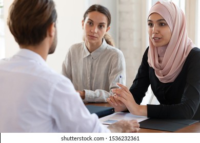 Asian muslim female hr manager interviewing job applicant consulting male client at diverse group meeting negotiations, ethnic businesswoman wear hijab speaking to partner, human resource concept