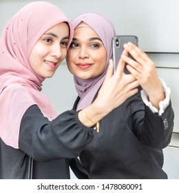 Asian Muslim girls taking a selfie. Outdoor setting.