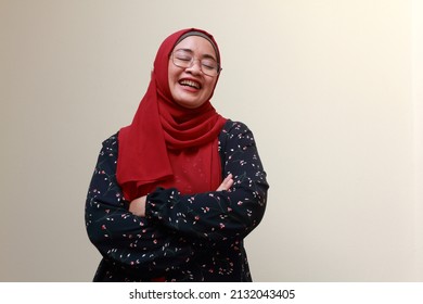 An Asian Muslim Lady Standing With Her Arms Crossed And Laughing. Happy And Satisfied Expression.