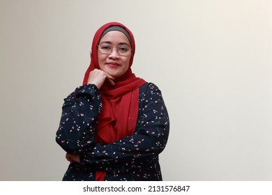 An Asian Muslim Lady Standing With One Hand On Her Chin And Confidence Expression On Her Face