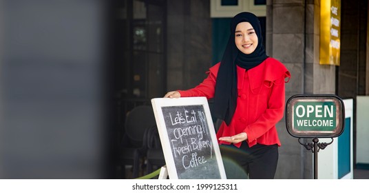 Asian Muslim Lady Standing Outside The Halal Restaurant Bakey And Cafe At Opening Sign To Welcome And Greeting The Customer With Copy Space