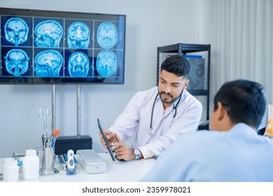 The Asian Muslim man doctor was sitting at the patient's examination table and was examining and talking about the patient with a smiling and worried face. - Shutterstock ID 2359978021