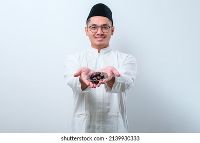 Asian Muslim Man Holding Dates Fruit Showing It To Forward, Over White Background