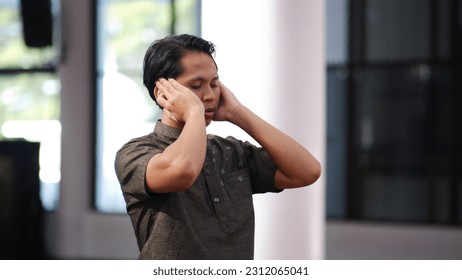 An Asian Muslim man is making the call to prayer. The name of azan, which converts the call to prayer for Muslims - Shutterstock ID 2312065041