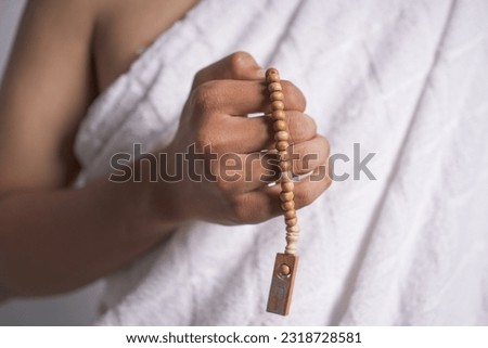 Asian Muslim man posing as ready for Hajj visiting Kaaba in Mecca. Asian muslim man wearing white ihram clothes hold praying beads. isolated white background