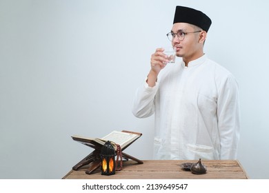 Asian Muslim Man Smiling And Thumbs Up While Going To Drink A Glass Of Water For Break Fasting Over White Background