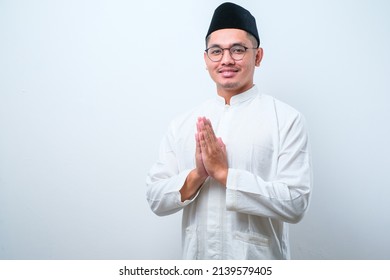 Asian Muslim man wearing glasses smiling to give greeting during Ramadan and Eid Al Fitr celebration over white background - Shutterstock ID 2139579405