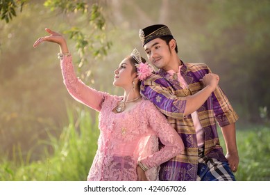 Asian Muslim man and woman wearing traditional dress in dancing action