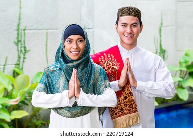 Asian Muslim Man And Woman Welcoming Guests Wearing Traditional Dress