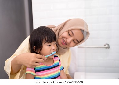 Asian Muslim Mom Brush Her Kid's Teeth In The Bathroom