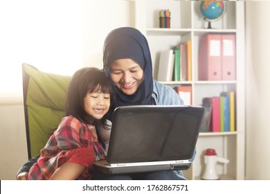 Asian Muslim Mom And Little Baby Girl Daughter Learning Online Or Watching Videos On Laptop, Happiness Between Mother And Kid, Single Parent Being Happy Concept