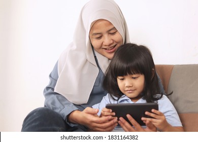 Asian Muslim Mom And Little Baby Girl Daughter Learning Online Or Watching Videos On Tablet Phone, Happiness Between Mother And Kid, Single Parent Being Happy Concept