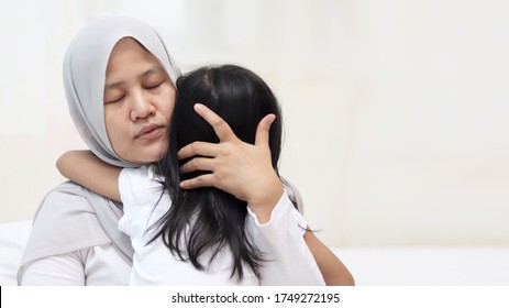 Asian Muslim Mother Wearing Hijab Calming Her Sad And Crying Daughter, Single Mom And Baby Girl Together