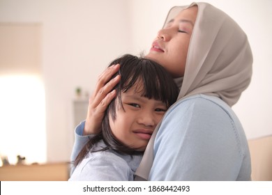 Asian Muslim Mother Wearing Hijab Calming Her Sad And Crying Daughter, Single Mom And Baby Girl Together