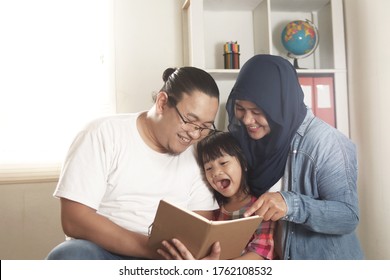 Asian Muslim Parent, Mother, Father And Child Are Reading A Book At Home, Happy Excited Expression, Family Education Concept