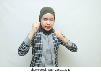 Asian Muslim woman clenching her fists with emotion and angry expression - Powered by Shutterstock