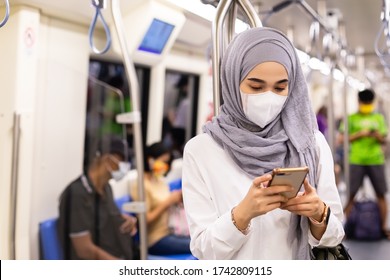 Asian Muslim Woman Wearing Medical Face Mask For Prevent Dust And Infection Virus, Using Smartphone In Subway Train Transit System Public.