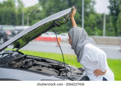 Asian Muslim women encountered a problem with the car driving the broken machine, opening the hood, checking the car, looking for the cause of the broken car.