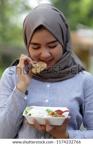 Asian Muslim women look happy while showing chicken geprek rice