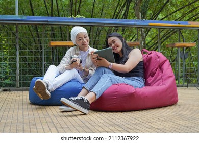 Asian Muslim Women Work And Hang Out Together With Other Asian Women. They're Looking At The Photos They're Working On. Diversity In Culture And Gender Concept. They Seem To Be Enjoying Nature.