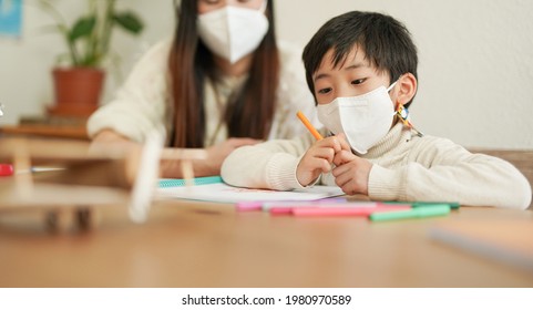 Asian Nanny Doing Drawing Activities With Little Child While Wearing Safety Face Mask For Coronavirus Outbreak - Concept Of Health Care And Daycare