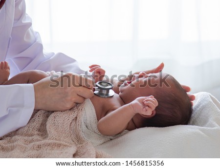 Asian newborn baby get sick crying during examine by pediatrician hold stethoscope, pediatric doctor monitoring heart pulse rate adorable infant crying in clinic, pediatrician with child concept