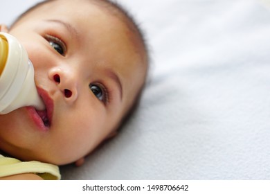 An Asian Newborn Baby Or Little Baby (about 4-6 Months) Drinking Milk From Bottle On Bed. The Concept Of Love, Care, Empathy, Lovely, Cute, Adorable And Pretty.