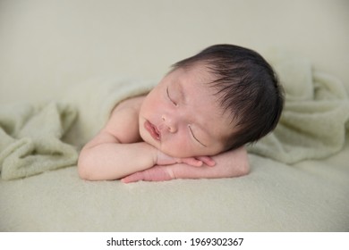 Asian Newborn Baby Sleep On Green Wrap Cloth.