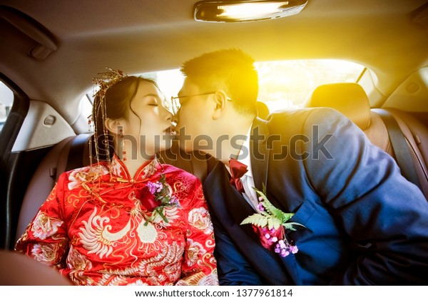 Asian newlyweds kissing in\
the car