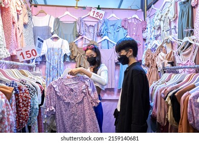 Asian Non Binary Couple Buying Clothes In An Urban Night Fair