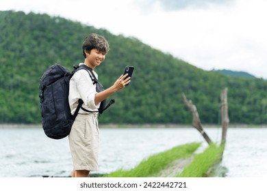 Asian non binary people relax and enjoy outdoor lifestyle travel forest mountain on summer holiday vacation. Generation z LGBTQ person using mobile phone taking selfie with beautiful nature at lake. - Powered by Shutterstock