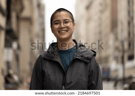 Asian non-binary woman smile happy face portrait on a city street