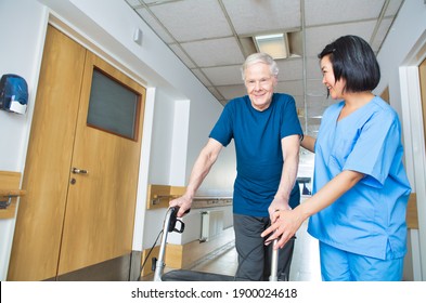 Asian Nurse Assisting Elderly Man With Walker Walking On The Hospital Floor.