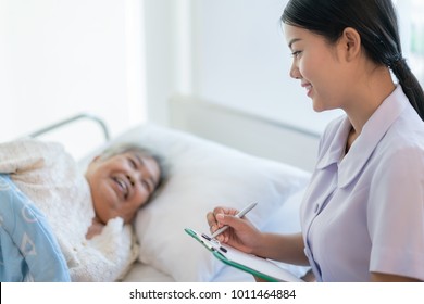 Asian nurse checking up the history of the disease elderly patient lying in bed. Elderly patient care and health lifestyle, medical concept.